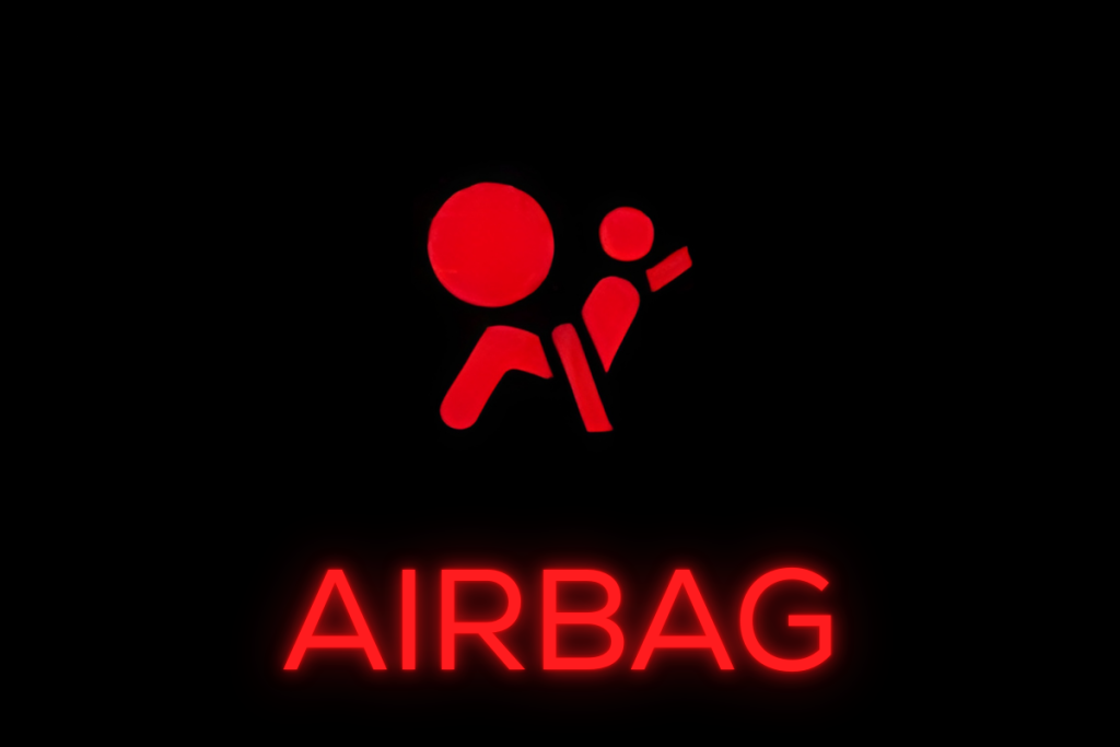 red airbag warning symbol showing seated passenger with airbag icon